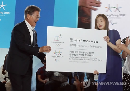 President Moon Jae-in (L) is presented with an enlarged version of his new business card listing him as an honorary ambassador for the PyeongChang Winter Olympic Games by former South Korean Olympic figure skating champion Kim Yu-na in an event held in PyeongChang, located some 180 kilometers east of Seoul, on July 24, 2017. (Yonhap)