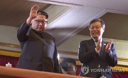 North Korean leader Kim Jong-un (L) waves at the crowd during a performance by a South Korean art troupe at East Pyongyang Grand Theatre in Pyongyang, in this photo captured from a pool report video on April 1, 2018, while South Korea's cultural minister, Do Jong-whan, applauds at his side. (Yonhap)