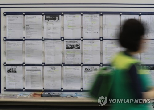 This file photo shows an unidentified person passing by a college bulletin board with job offerings. (Yonhap)