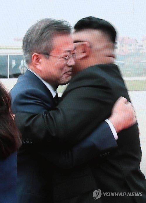 South Korean President Moon Jae-in (left) and North Korean leader Kim Jong-un embrace at Pyongyang's Sunan International Airport, in this image from live television coverage shown at the press center in Seoul, Sept. 18, 2018. (Yonhap)