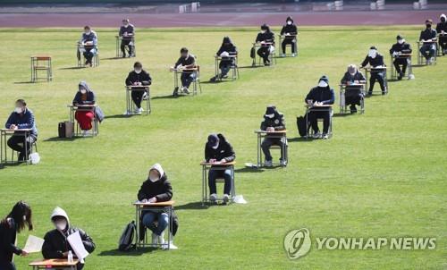 More than 100 job applicants, seated at a safe distance from one another, take a written exam as part of the recruitment process at the city-run Ansan Urban Corp. at a football stadium in Ansan, about 40 kilometers south of Seoul, on April 4, 2020. The urban planning firm decided to hold the test outdoors to prevent the spread of the coronavirus. (Yonhap)