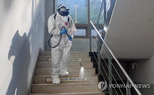 A health worker disinfects a stairway at a high school in Busan on Aug. 13, 2020. (Yonhap)