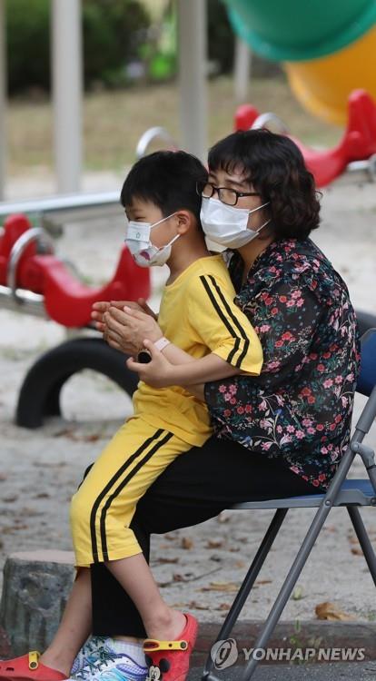 A mother and her son wait for tests for the new coronavirus at an elementary school in Hwasun, South Jeolla Province, southwestern South Korea, on Aug. 24, 2020. Students and teachers of an elementary school were to receive such tests for the new coronavirus after a teacher tested positive for the virus. (Yonhap)