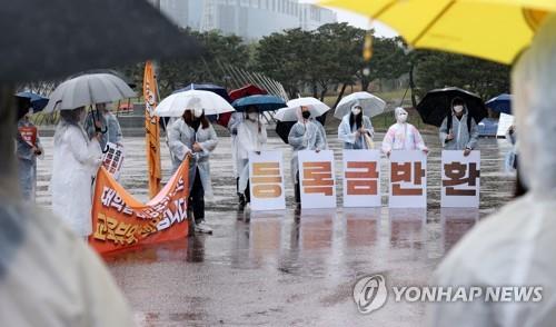 In this file photo, students hold signs demanding tuition refunds in Seoul on April 3, 2021. (Yonhap)