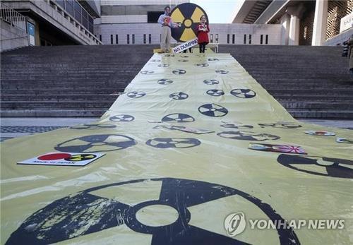 In this file photo, South Korean activists wear masks depicting incumbent and former Japanese prime ministers during a rally in Seoul on Oct. 25, 2021, to condemn Japan's plan to release radioactive water into the sea from its crippled Fukushima nuclear power plant. (Yonhap)