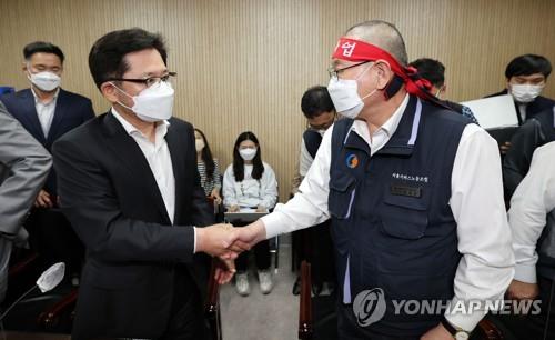 Representatives of unionized bus drivers and bus operators in Seoul shake hands at a National Labor Relations Commission office on April 26, 2022, after reaching an agreement on pay hikes. (Yonhap) 
