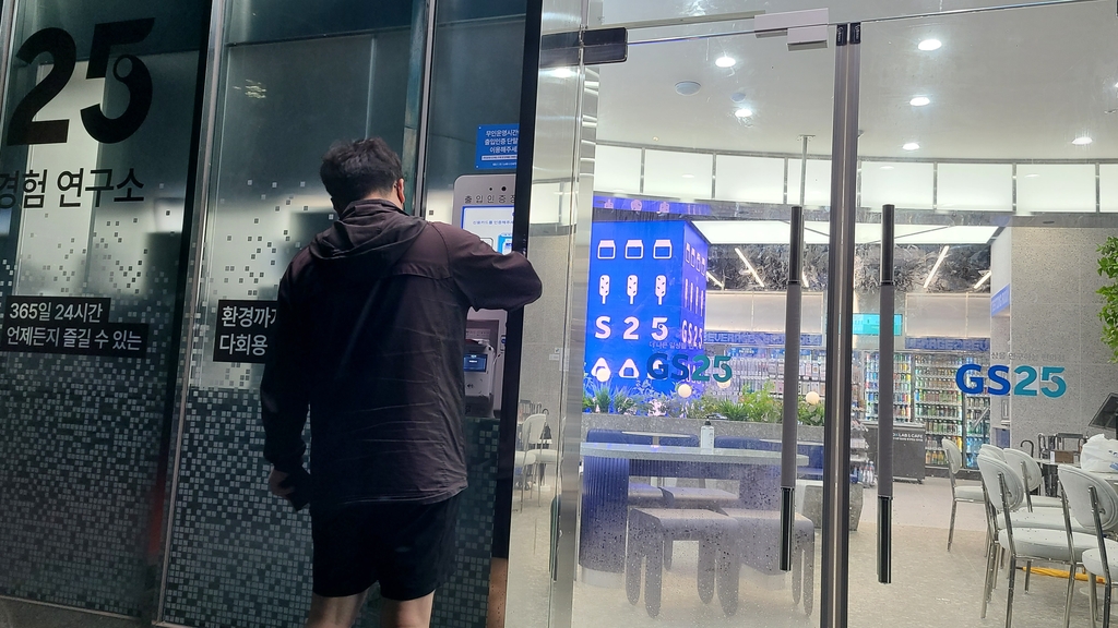 A person scans a credit card on a card reader device before entering the GS25 DX LAB store in Yeoksam, south of Seoul, on June 30, 2022. (Yonhap)