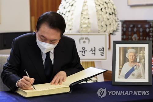 This photo, provided by the presidential office, shows President Yoon Suk-yeol signing a condolence book for late British Queen Elizabeth II in front of a memorial altar for her set up at the British Council in Seoul on Sept. 9, 2022. (PHOTO NOT FOR SALE) (Yonhap)