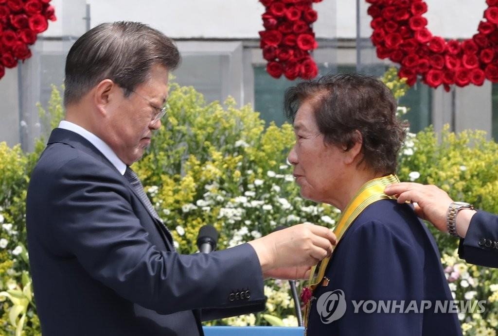 Le président Moon Jae-in (à g.) remet une médaille à Bae Eun-shim, la mère de Lee Han-yeol qui est décédé après avoir été blessé par une grenade lacrymogène durant une manifestation pro-démocratie en 1987, lors d'une cérémonie tenue au Mémorial pour la démocratie et les droits de l'Homme dans l'arrondissement de Yongsan, à Séoul, le mercredi 10 juin 2020.