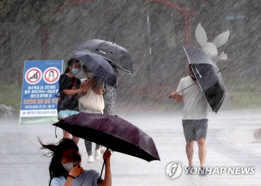 Des piétons essaient de tenir leur parapluie sous de fortes pluies, accompagnées de vents violents à Busan, dans le sud-est du pays, le lundi 10 août 2020.