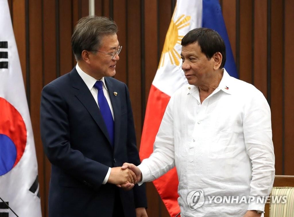 フィリピンのドゥテルテ大統領（右）と握手する文大統領＝１３日、マニラ（聯合ニュース）
