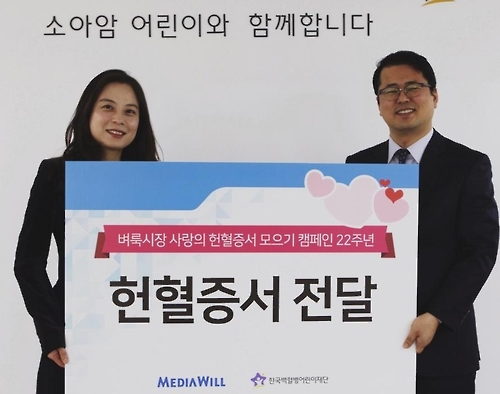 벼룩시장 관계자(사진 왼쪽)가 백혈병 어린이재단 인사에 헌혈증서를 전달하는 모습