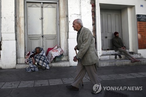 23일(현지시간) 노숙자가 진을 치고 있는 그리스 아테네의 거리를 한 노인이 지나가고 있다. [AP=연합뉴스] 