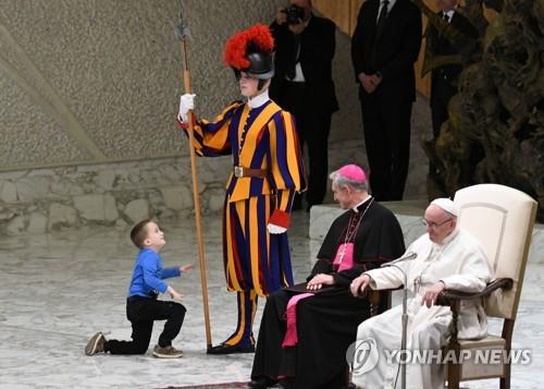 28일 바티칸에서 열린 수요 일반알현에서 한 6세 꼬마가 교황이 앉아 있는 단상 위로 올라와 장난을 치고 있다. [AFP=연합뉴스] 