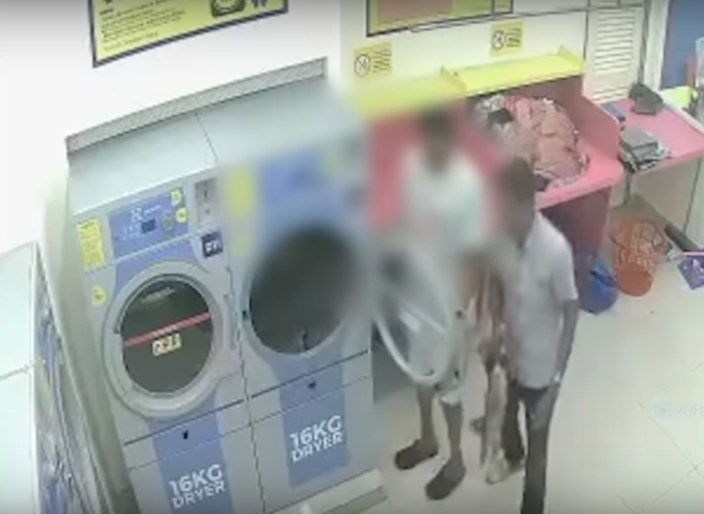 2018년 9월 11일 밤 말레이시아 슬랑오르 주의 한 세탁소에서 현지인 남성 두 명이 고양이를 잡아 세탁물 건조기에 집어넣고 있다. [현지방송 영상 캡처=연합뉴스]