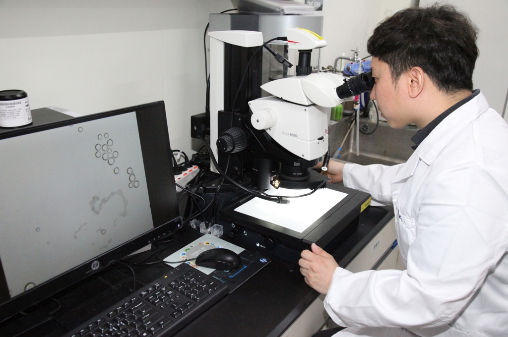 박찬우 박사가 미세 수중로봇을 현미경으로 확인하는 모습