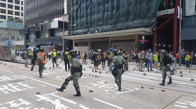 도로 위에 시위대가 흩뜨려 놓은 보도블록을 치우는 홍콩 경찰