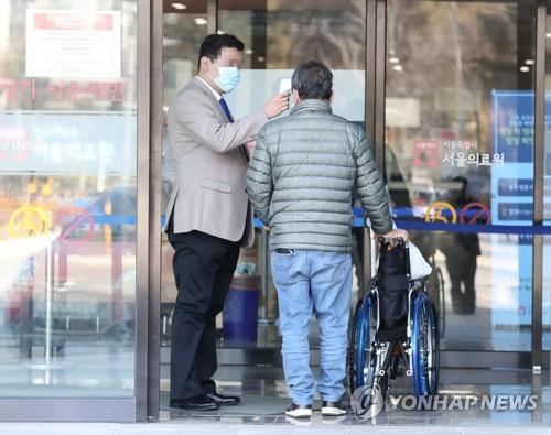 병원 관계자가 내원객의 체온을 측정하는 모습.