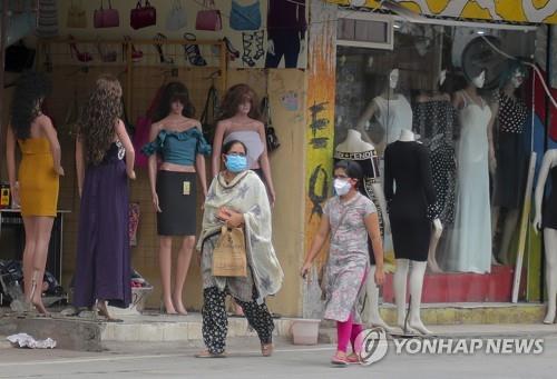 인도 하이데라바드에서 마스크를 쓰고 상점 앞을 지나가는 여성. [AP=연합뉴스]