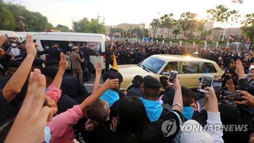 수티다 왕비가 탄 차량을 향해 세 손가락 경례를 하는 시위대