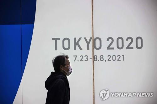 (도쿄 AFP=연합뉴스) 일본에 신종 코로나바이러스 감염증(코로나19) 긴급사태가 발효 중인 가운데 22일 도쿄에서 마스크를 쓴 행인이 도쿄올림픽 홍보물 앞을 지나고 있다.