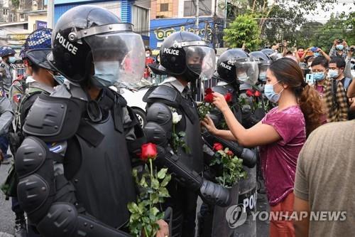 양곤의 시위대가 행진을 막은 경찰들에게 장미꽃을 달아주고 있다. 2021.2.6