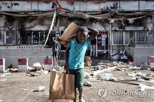 6일 세네갈 소년이 다카르의 약탈당한 슈퍼마켓에서 종이백을 갖고 나오고 있다. 