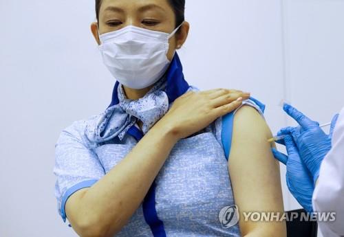 (도쿄 로이터=연합뉴스) 전일본공수(ANA) 객실 승무원이 13일 일본 도쿄도(東京都) 하네다(羽田)공항에 있는 ANA 사무실에서 신종 코로나바이러스 감염증(코로나19) 백신을 맞고 있다.