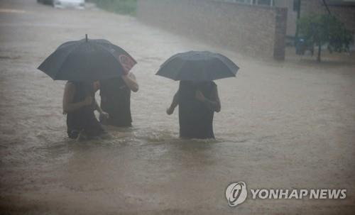 게릴라성 집중호우가 쏟아진 지난 18일 오전 강릉 시내에서 시민들이 물에 잠긴 도로를 건너고 있다. [연합뉴스 자료사진]