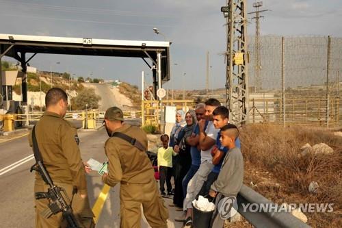 분리 장벽 반대편의 올리브밭에 가기 위해 대기 중인 팔레스타인 주민들(오른쪽)과 이스라엘 경찰관들.[AFP 연합뉴스 자료사진]