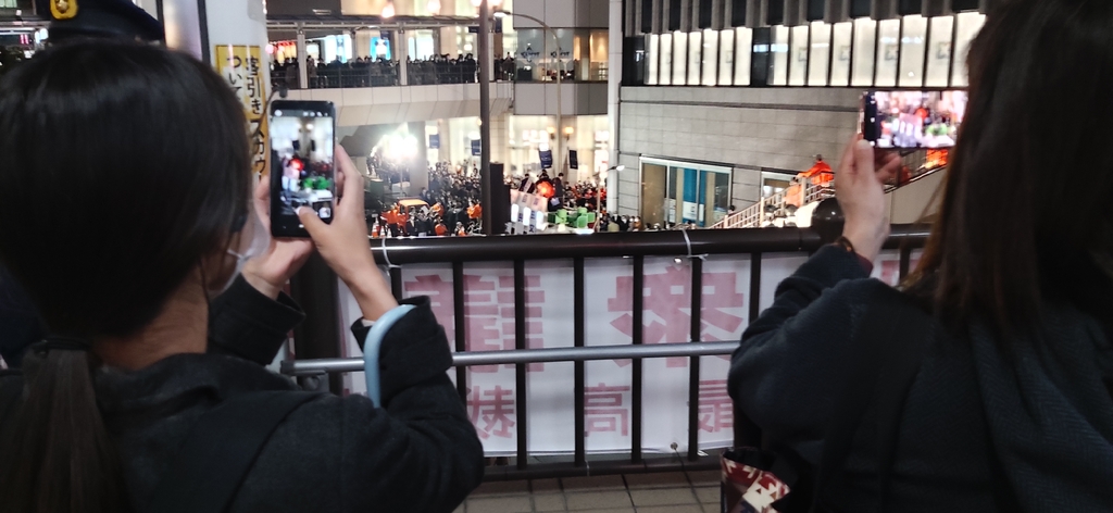 (도쿄=연합뉴스) 일본 집권 자민당 총재인 기시다 후미오 총리가 26일 저녁 JR다치카와역 주변에서 유세하는 모습을 스마트폰 카메라에 담는 행인들. 