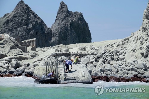 화산분화 후 재로 뒤덮인 뉴질랜드 화이트섬. 사진은 지난 9일 구조대가 선착장에서 고무보트로 부상자들을 나르는 모습 / AP=연합뉴스 자료사진