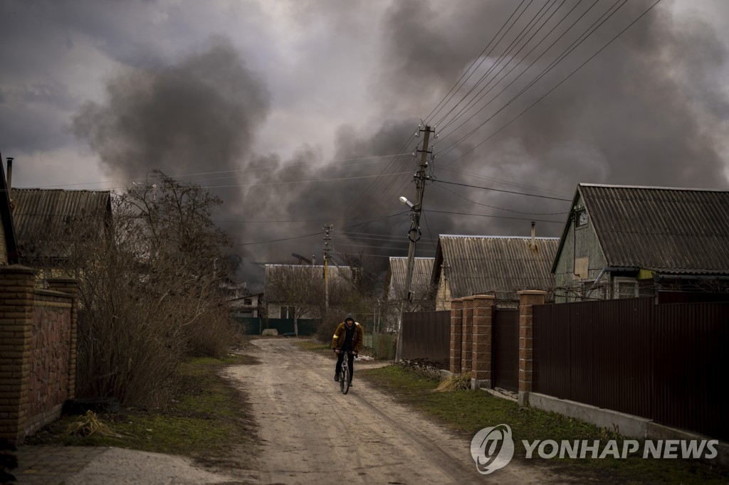 2022년 3월 6일 러시아군의 포격으로 짙은 연기가 솟아오르는 우크라이나 소도시 이르핀 시내에서 한 남성이 자전거를 탄 채 피해지역 반대 방향으로 이동하고 있다. [AP 연합뉴스, 재판매 및 DB 금지]