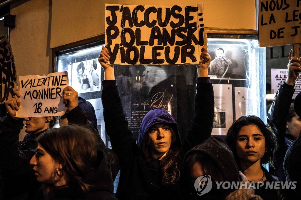 작년 11월 프랑스 파리 시내의 '장교와 스파이' 상영관 앞에서 반대시위를 하는 여성들. 가운데 여성이 로만 폴란스키 감독의 '장교와 스파이'의 원제 '나는 고발한다'에 '폴란스키는 강간범'이라는 문구를 더한 푯말을 들고 있다. [AFP=연합뉴스 자료사진]