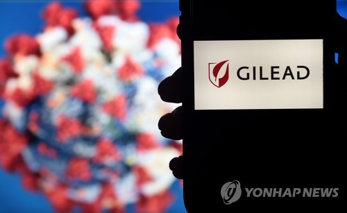 코로나바이러스 모형 옆에 미 제약회사 길리어드 사이언스의 로고가 표시돼있다. [AFP=연합뉴스