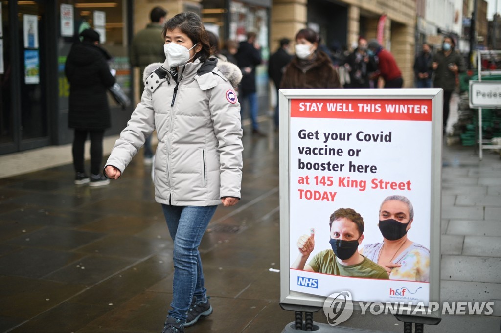 (런던 AFP=연합뉴스) 3일(현지시간) 영국 런던에 있는 코로나19 백신 접종 센터 밖을 한 여성이 걸어가고 있다. 2021.12.3. photo@yna.co.kr