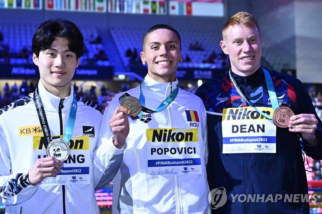 In this AFP photo, Hwang Sun-woo of South Korea (L) poses with his silver medal from the men's 200m freestyle at the FINA World Championships at the Duna Arena in Budapest on June 20, 2022. Hwang stands next to gold medalist, David Popovici of Romania (C), and bronze medalist, Tom Dean of Britain. (Yonhap)