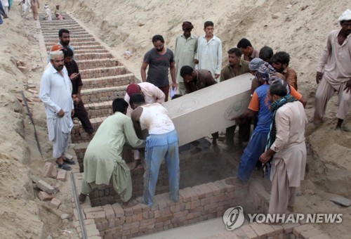 27일(현지시간) 파키스탄 바하왈푸르에서 주민들이 이틀전 발생한 유조차 기름 유출 화재의 신원미확인 희생자 125명의 관을 묻고 있다.[EPA=연합뉴스]