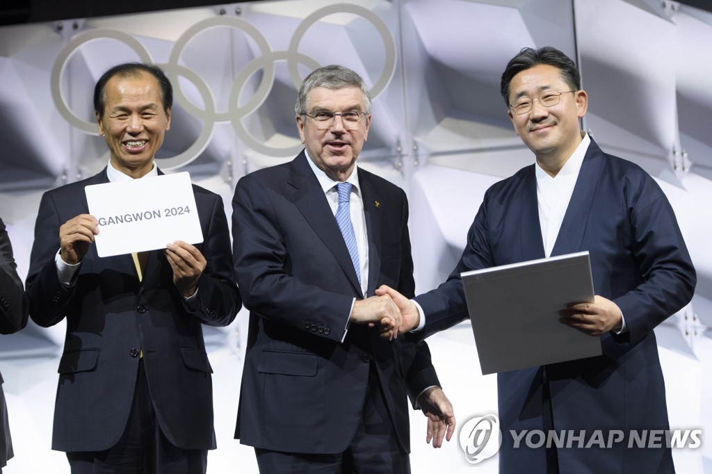 In this EPA file photo from Jan. 10, 2020, Choi Moon-soon (L), governor of South Korea's Gangwon Province, holds a card showing the name of Gangwon Province of South Korea as the host of the 2024 Winter Youth Olympics, following an election at the 135th International Olympic Committee (IOC) Session in Lausanne, Switzerland. Others with Lee are Thomas Bach (C), president of the IOC, and Park Yang-woo, South Korean minister of culture, sports and tourism. (Yonhap)