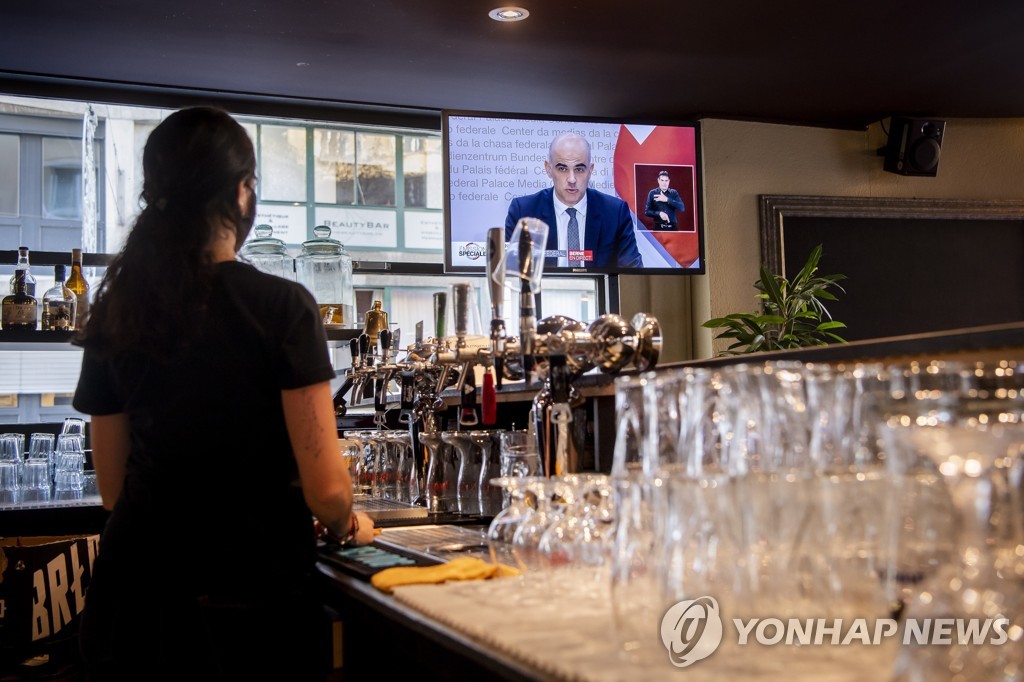 스위스의 한 식당 종업원이 보건장관의 코로나19 대책 발표를 지켜보고 있다.