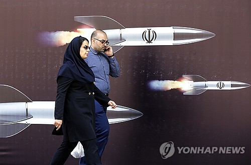 미사일이 그려진 벽화 앞을 걷는 이란 시민들