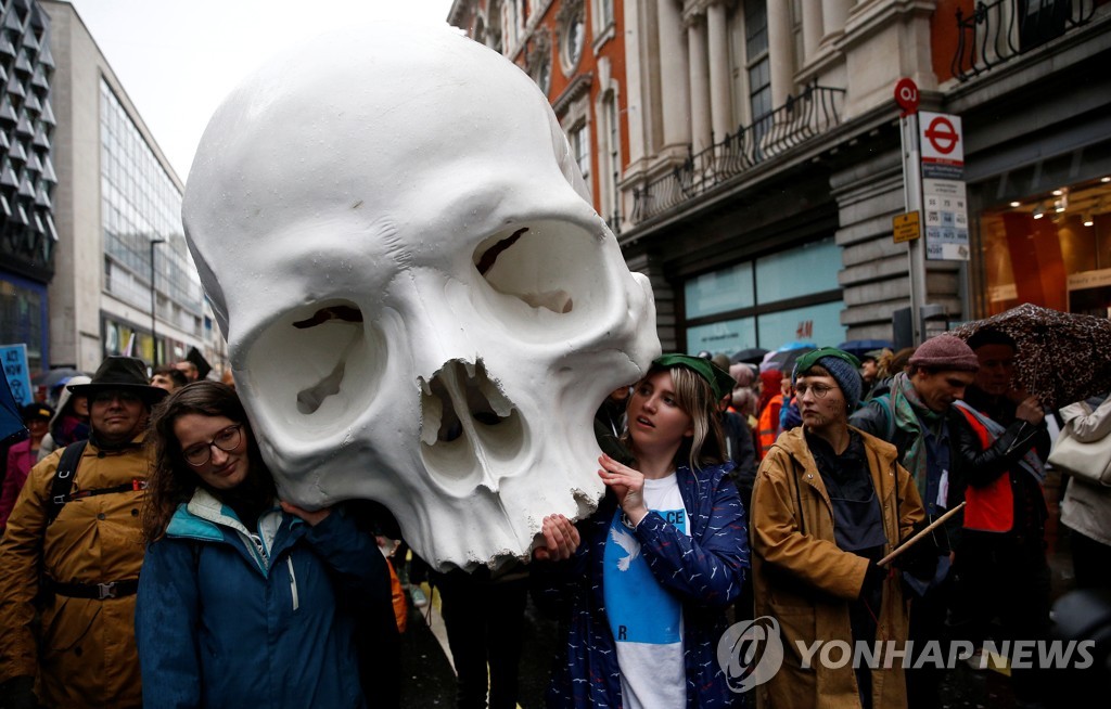 12일(현지시간) 영국 런던에서 열린 '멸종저항' 시위에 참여한 활동가들이 거대한 해골을 앞세우고 거리 행진을 하는 모습 [로이터=연합뉴스]