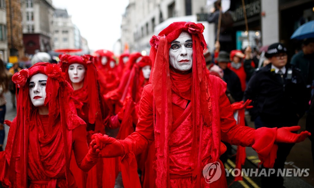 12일(현지시간) 영국 런던에서 열린 '멸종저항' 시위에 참여한 '붉은 여단' 활동가들이 붉은색 천으로 온몸을 감싼 의상을 입고 거리를 걷는 모습 [로이터=연합뉴스]
