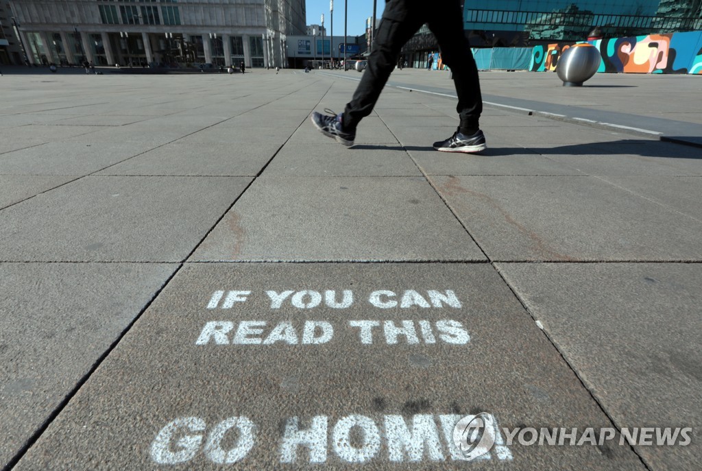 베를린의 텅 빈 알렉산더플라츠 광장에서 '집으로 가라'는 의미의 그라피티 인근을 걷는 시민 [로이터=연합뉴스] 