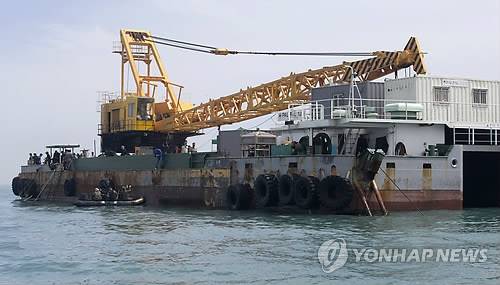 29일 오후 전남 진도군 조도면 동거차도 앞 세월호 침몰 현장에서 이날 새벽 투입된 팔팔 128호 바지선 관계자들이 세월호 창문을 절개하기 위한 절단기를 수중으로 내려 작업하고 있다.