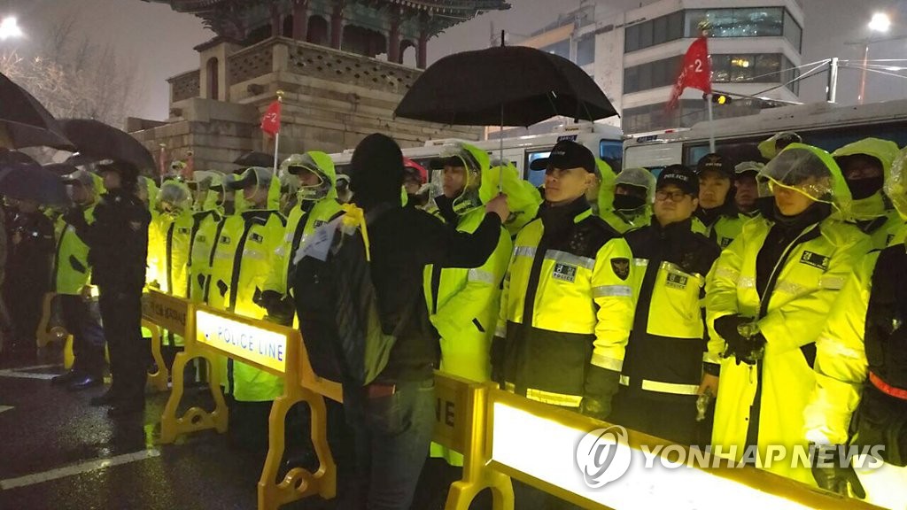 의경에게 우산 씌워주는 촛불집회 참가자