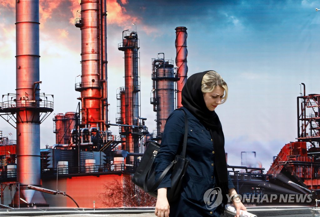 (테헤란 EPA=연합뉴스) 6일(현지시간) 테헤란에서 열린 '제23회 이란 석유·가스·석유화학 국제전시회' 행사장에서 한 여성이 이란 석유화학시설 사진 앞을 지나고 있다. 