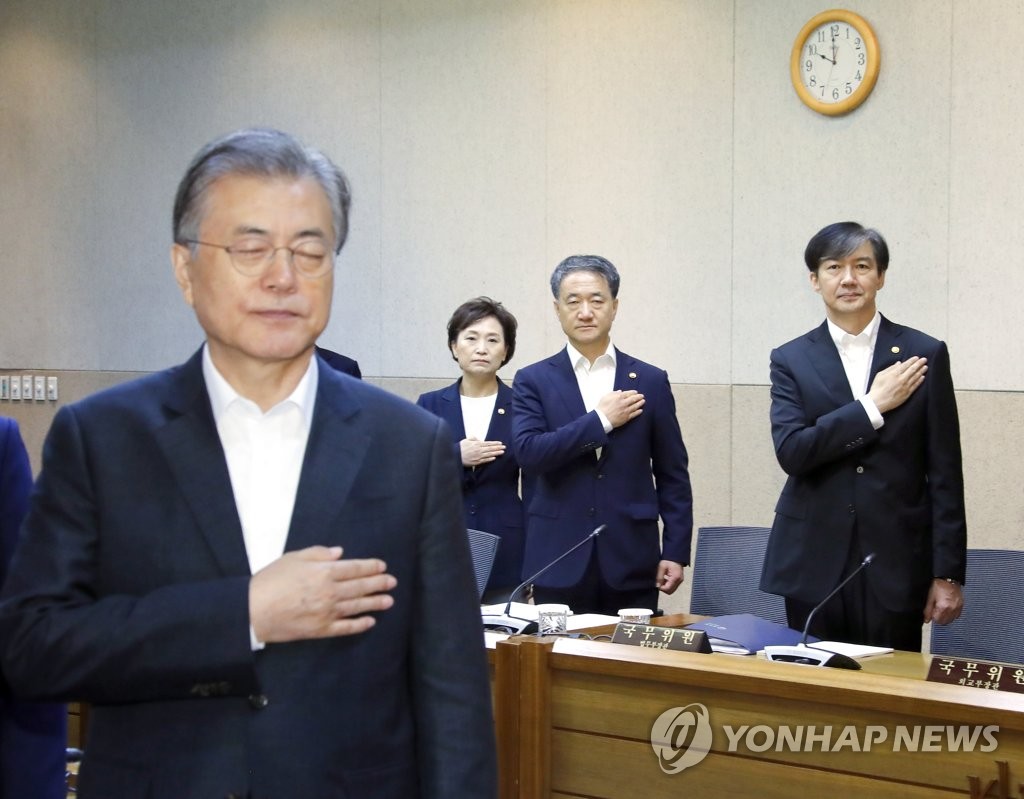 In this file photo, dated Sept. 10, 2019, President Moon Jae-in (L) salutes to South Korea's national flag during a Cabinet meeting, attended by Justice Minister Cho Kuk (R), at the Korea Institute of Science and Technology in Seoul. (Yonhap)