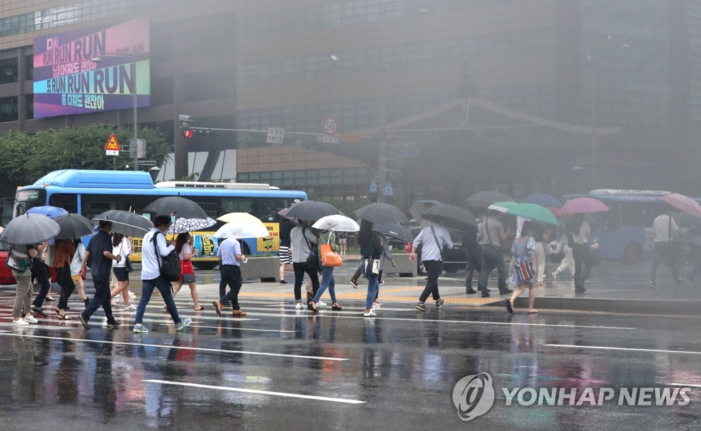 傘をさして通勤する人々＝６日、ソウル（聯合ニュース）