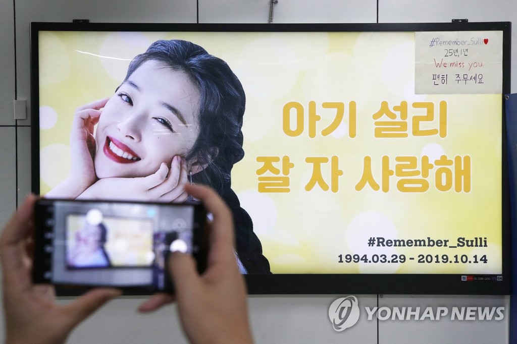 ソルリさんを追悼する看板を撮影する市民＝１４日、ソウル（聯合ニュース）